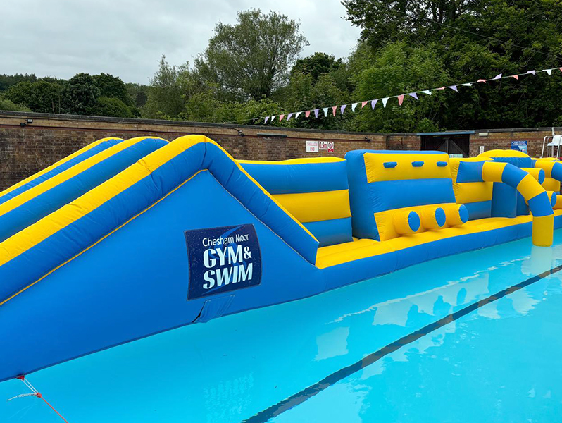 Blue and yellow inflatable obstacle course in open air pool
