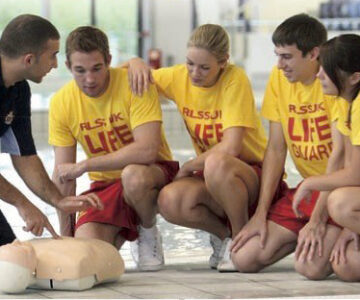 Lifeguarding course attendes on poolside with instructor