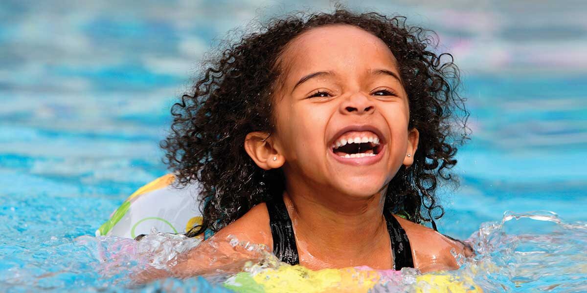 Happy young girl playing in pool
