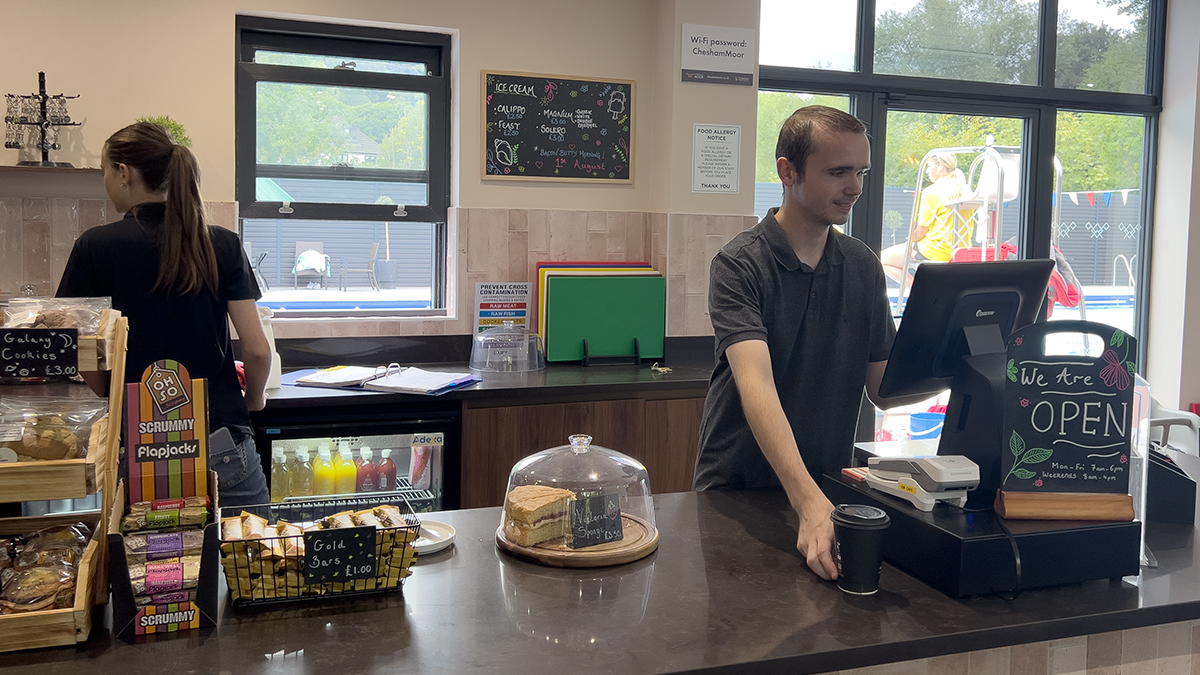staff at cafe counter and pool in the background visible through window
